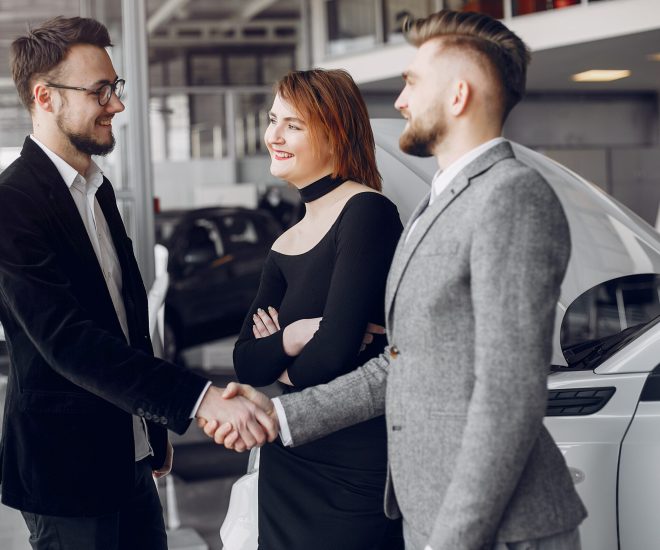 Couple in a car salon. Family buying the car. Elegant woman with her husband. Assistant with a clients